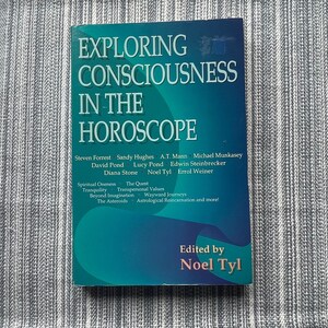 May include: A teal blue book titled "Exploring Consciousness in the Horoscope" with the names of the authors and editors listed on the cover.