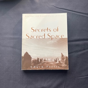 May include: A book titled "Secrets of Sacred Space" by Chuck Pettis. The cover features a sepia-toned image of a landscape with rock formations. The title is in a large, elegant font.
