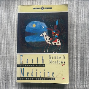 May include: A paperback book titled "Earth Medicine" by Kenneth Meadows. The cover features an illustration of a figure on a spotted horse against a blue and black background with a moon. The book's subtitle reads "A Shamanic Way to Self Discovery."