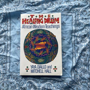 May include: A book titled "The Healing Drum: African Wisdom Teachings" with a colorful circular design on the cover. The book is white with red, green, and blue text. The authors' names, Yaya Diallo and Mitchell Hall, are also printed on the cover.