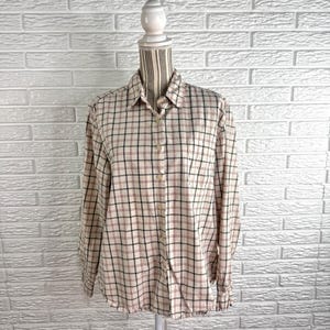 May include: A long-sleeved button-down shirt featuring a beige base with a grid pattern of thin black and red lines. The shirt has a standard collar, a front button placket, and buttoned cuffs, displayed on a mannequin torso against a white brick wall.