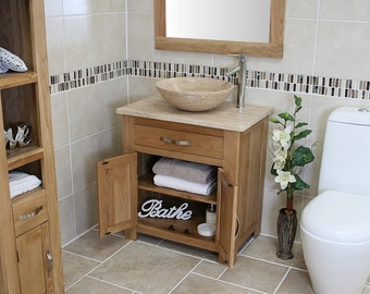 May include: A bathroom vanity with a white ceramic sink and a wooden cabinet with two doors. The cabinet has a drawer and two shelves. The vanity is in a bathroom with white tile walls and a white toilet.