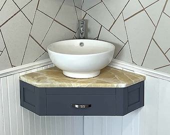 May include: A white ceramic corner sink with a single faucet and a dark blue cabinet with a drawer underneath. The sink is mounted on a beige countertop.