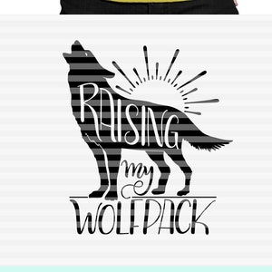 Puede incluir: Una camiseta amarilla con un gráfico de lobo negro y el texto "Raising my Wolfpack". La imagen también muestra un gráfico de lobo en blanco y negro y una taza turquesa con el mismo diseño. También se ve el texto "SVG PNG CUTTABLE PRINTABLE AWESOME".