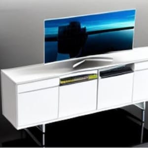 May include: A modern white entertainment center with a curved screen television. The TV has a blue and black image on the screen. The cabinet has three doors and open shelves for media components.