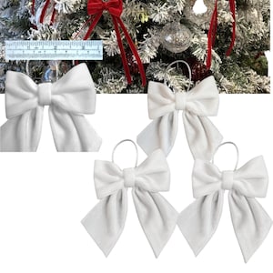 Peut inclure: Trois nœuds en velours blanc avec des boucles pour accrocher à un arbre de Noël. Les nœuds mesurent environ 15 cm de large.