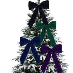 May include: Four velvet bows in navy, emerald green, deep purple, and black are displayed against a snowy Christmas tree backdrop. Each bow has long, flowing tails, adding a touch of elegance to holiday decorations.