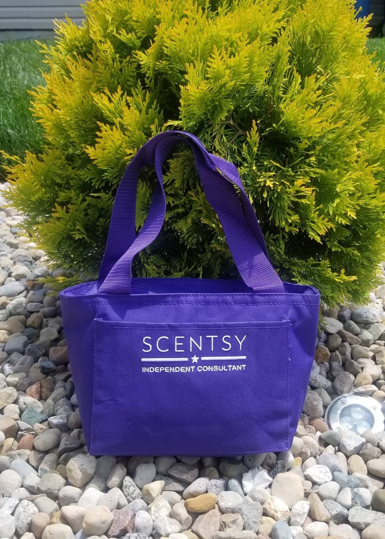 Puede incluir: Una bolsa de mano de color morado con texto blanco que dice "Scentsy Independent Consultant".