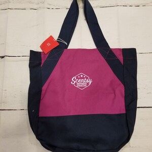 May include: A pink and navy blue canvas tote bag with the text "Scentsy Independent Consultant" in white.