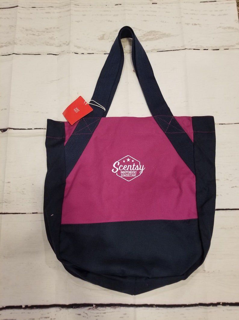 May include: A pink and navy blue canvas tote bag with the text "Scentsy Independent Consultant" in white.