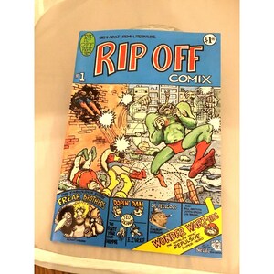 May include: A vintage comic book titled "RIP OFF COMIX #1". The cover features colorful illustrations of cartoon characters in action, with text including "FREAK BROTHERS" and "WONDER WART-HOG". The comic is in good condition.