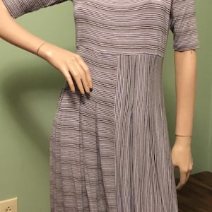 May include: A striped, gray and white, short-sleeved dress with a scoop neck. The dress has a gathered skirt and a unique design with vertical stripes on one side and horizontal stripes on the other.