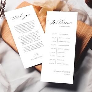 May include: Two white wedding cards with black calligraphy. One says "thank you" and includes a message. The other says "Welcome to our wedding" and lists the schedule. Both cards are on a wooden surface.