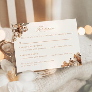 May include: A wedding RSVP card in cream with floral decorations and the word "Response". The card has sections for accepting or declining the wedding reception and welcome party, with a note about dietary requirements.