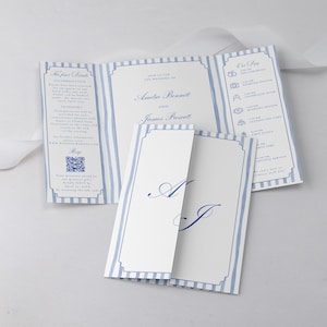 May include: A tri-fold wedding invitation with a blue and white striped pattern. The invitation features the names Amelia Bennett and James Prescott, along with event details and a QR code. The invitation is open, displaying the contents.