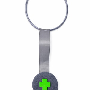 Pode incluir: Um colar cinzento em forma de estetoscópio com uma cruz verde num círculo de feltro cinzento. O colar tem uma fita cinzenta e uma banda circular cinzenta com pontas de ouvido cinzentas. A joia de tema médico está sobre um fundo branco.