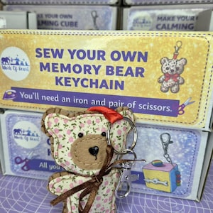 May include: A Memory Bear keychain kit. The bear is made of floral fabric with a brown centre and a brown ribbon. The kit includes a keychain ring and a clasp. The packaging reads "Sew Your Own Memory Bear Keychain."