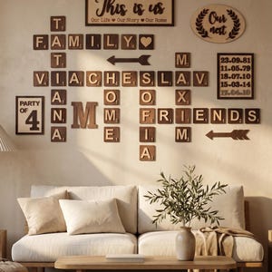 May include: Wooden wall art arrangement with the words "This is us", "Family", and "Friends" displayed with individual letter tiles. Includes a sofa, coffee table, and vase with greenery.