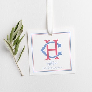 May include: Square gift tag with a white background, a blue and red border, and a monogram in the center. The monogram features the letters "H" and "C" in pink and blue. The text "a gift from HONOR CANON" is below the monogram.