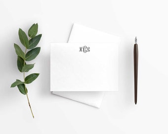 May include: A white card with a black monogram "HGS" printed on it. A green leafy branch and a brown pen are also in the image.