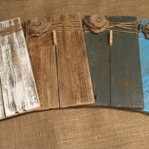 May include: Four rustic wooden picture frames with twine and burlap flowers. Each frame has a different color of paint: white, brown, gray, and blue.