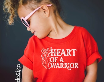 May include: A red t-shirt with a white graphic of a heart and the text "HEART OF A WARRIOR".