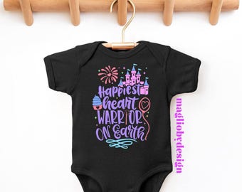 May include: Black baby onesie with a colorful graphic that says "Happiest heart warrior on earth". The graphic includes a cupcake, a heart balloon, fireworks, and a pink castle.