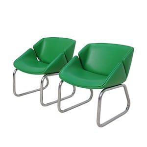 May include: Two green chairs with chrome frames. The chairs have a unique, modern design with a curved back and seat.