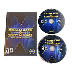 May include: A PC game set featuring the game case and two discs. The case is black with the game title "Command & Conquer: The First Decade" in gold and white. The discs are blue with the game title and EA logo.