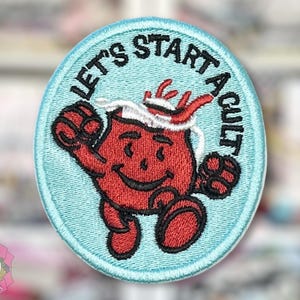 May include: Embroidered patch with a light blue background and a red cartoon character. The text "LET'S START A CULT" is in black, arched around the top. The character is red with a white headband and black gloves and shoes.