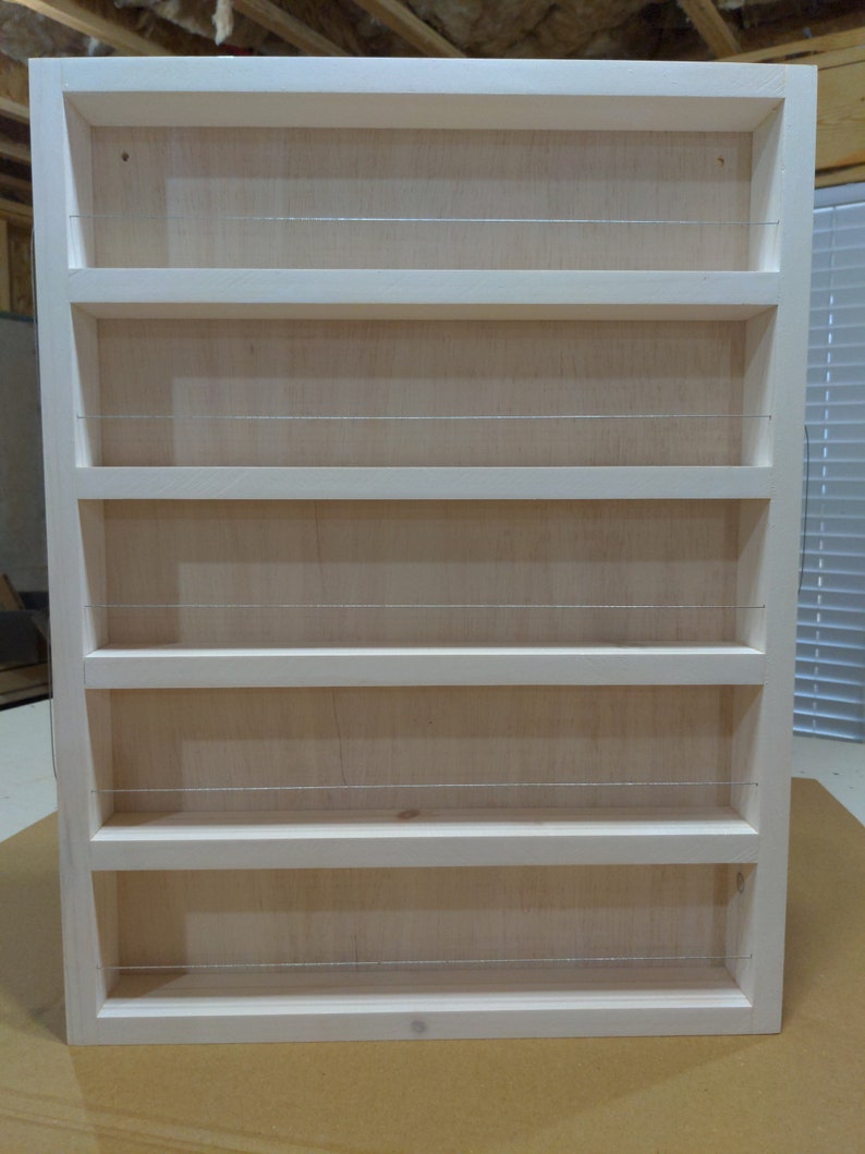 May include: White wooden spice rack with five shelves and wire dividers. The rack is empty.