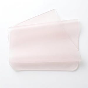 May include: A rectangular, semi-transparent sheet with a soft, pale pink hue. The material appears flexible and smooth, featuring rounded corners and a folded edge that creates a layered, translucent effect across the surface of the object.