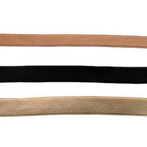 May include: Three elastic bands in different colors: beige, black, and a lighter beige. The bands are all flat and have a woven texture.