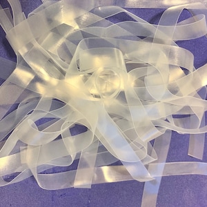 May include: A pile of clear elastic bands, also known as rubber bands, on a purple surface.