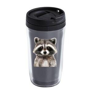 May include: A black and gray travel mug with a raccoon face design. The raccoon has black eyes, a black nose, and gray fur.