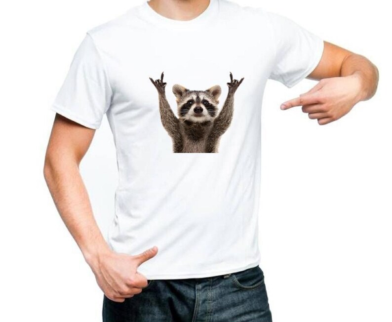 May include: White t-shirt with a graphic of a raccoon making a rock and roll hand gesture.