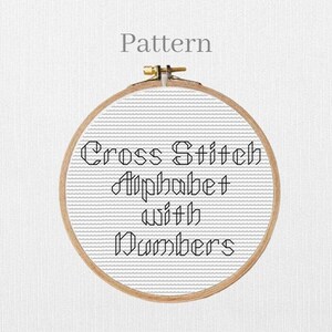 Könnte beinhalten: Ein Kreuzstichmuster, das in einem hölzernen Stickrahmen dargestellt wird. Der Text "Cross Stitch Alphabet with Numbers" ist mit schwarzem Faden auf einem weißen Stoffhintergrund gestickt. Das Wort "Pattern" steht über dem Rahmen.