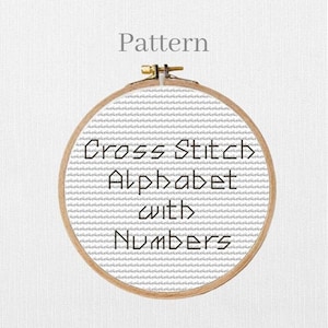 Può includere: Un telaio da ricamo circolare in legno contenente un tessuto bianco con un motivo grigio ripetitivo. Il testo "Pattern" appare sopra il telaio, e il testo "Cross Stitch Alphabet with Numbers" è centrato in nero sul tessuto all'interno.