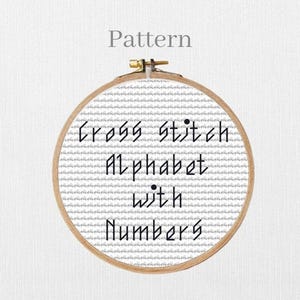 May include: An embroidery hoop with a cross-stitch design. The text on the pattern reads "Cross Stitch Alphabet with Numbers" in black. The word "Pattern" is above the hoop.