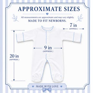 Peut inclure: Une grenouill&egrave;re blanche &agrave; manches longues avec bordure festonn&eacute;e bleue. Le texte indique APPROXIMATE SIZES, MADE TO FIT NEWBORNS et MADE WITH LOVE. Les dimensions indiqu&eacute;es sont 50,8 cm de longueur, 22,86 cm de largeur et 17,78 cm de manche.