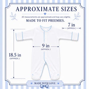 Peut inclure: Une grenouill&egrave;re blanche &agrave; manches longues avec une bordure festonn&eacute;e bleu clair. Le texte indique APPROXIMATE SIZES, MADE TO FIT PREEMIES et MADE WITH LOVE. Les dimensions indiqu&eacute;es sont 18,5 pouces de longueur, 9 pouces de largeur et 7 pouces.