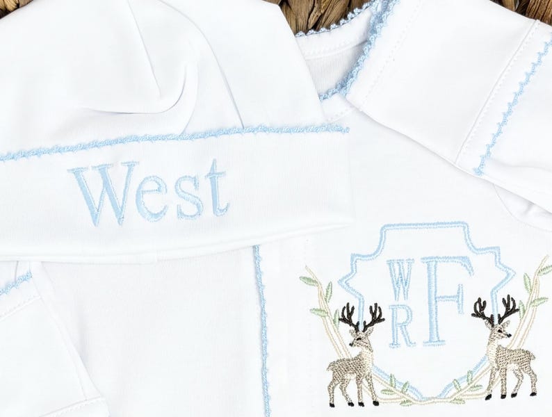 Peut inclure: Un ensemble pour b&eacute;b&eacute; compos&eacute; d'un bonnet et d'un v&ecirc;tement &agrave; manches longues blancs avec des bordures bleu clair. Le bonnet porte le nom West brod&eacute; en bleu clair. Le v&ecirc;tement pr&eacute;sente un &eacute;cusson bleu clair avec les lettres WRF et deux cerfs.