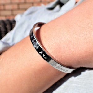 May include: A silver bangle bracelet engraved with the inscription "I love you back xx" and "Melanie".