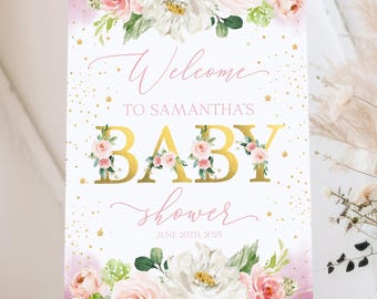 May include: A baby shower welcome sign on a wooden easel. The sign features floral arrangements and gold lettering that reads "Welcome to Samantha's Baby Shower, June 20th, 2023". The background is a soft pink with gold star accents.