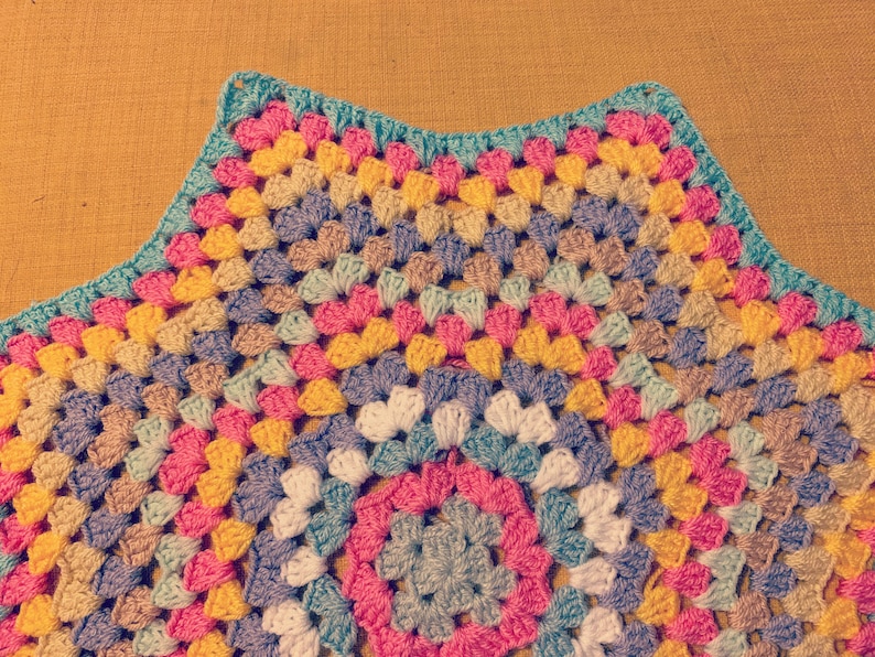 May include: A colorful crocheted blanket with a starburst pattern in shades of pink, yellow, blue, and green.