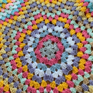 May include: A colorful crocheted blanket with a circular pattern in shades of pink, yellow, blue, green, and purple.
