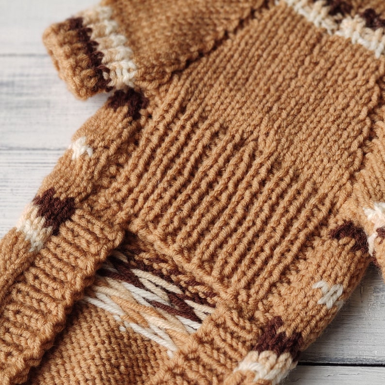 May include: A brown knitted jumper with white and brown stripes. The jumper has a textured knit pattern.