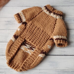 May include: A brown knitted dog sweater with white and brown stripes. The sweater has a turtleneck collar and a loose fit.