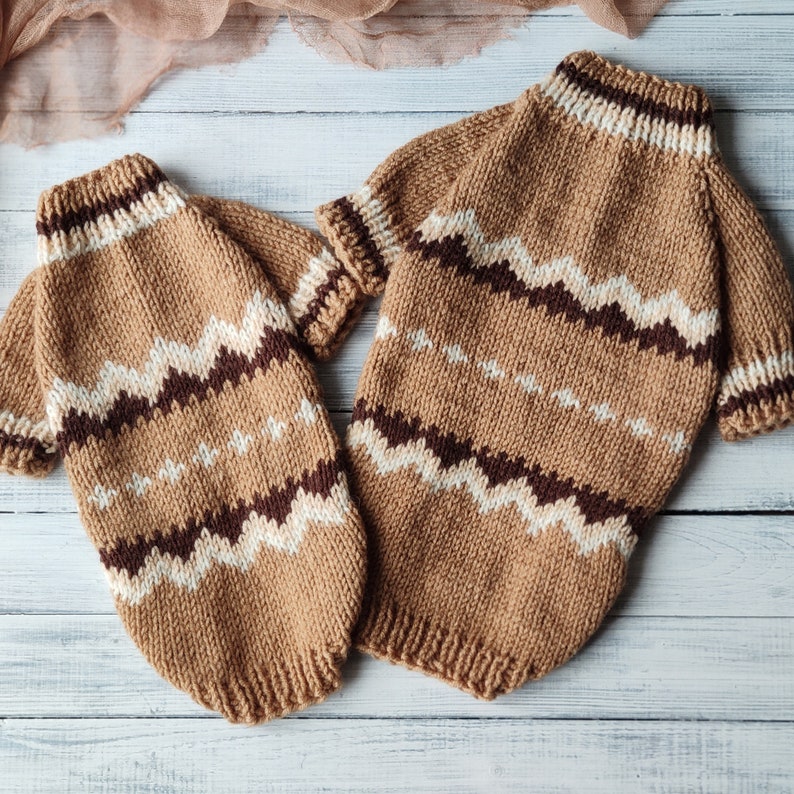 May include: Two brown knitted jumpers with a white and brown chevron pattern. The jumpers are made of a soft, cosy yarn and are perfect for keeping warm in the winter.