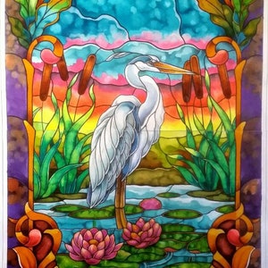 May include: A stained glass artwork depicting a white heron standing in a pond with lily pads and reeds. The background features a blue sky with clouds and a sunset.